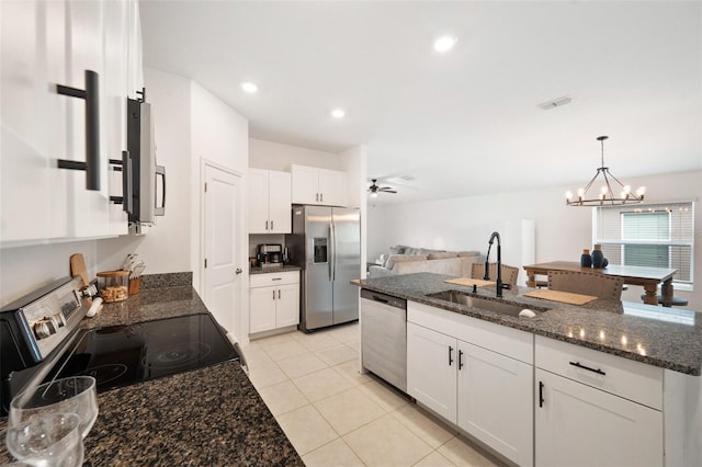 kitchen with appliances with stainless steel finishes, dark stone counters, ceiling fan with notable chandelier, sink, and white cabinets