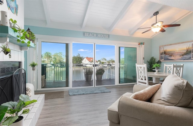 living room featuring a water view, vaulted ceiling with beams, ceiling fan, plenty of natural light, and wood-type flooring