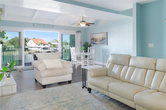 living room featuring ceiling fan, dark hardwood / wood-style flooring, a water view, and beamed ceiling