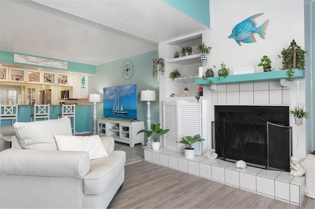 living room with a fireplace, wood-type flooring, and a textured ceiling