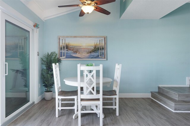 dining room featuring ceiling fan, wood-type flooring, and vaulted ceiling