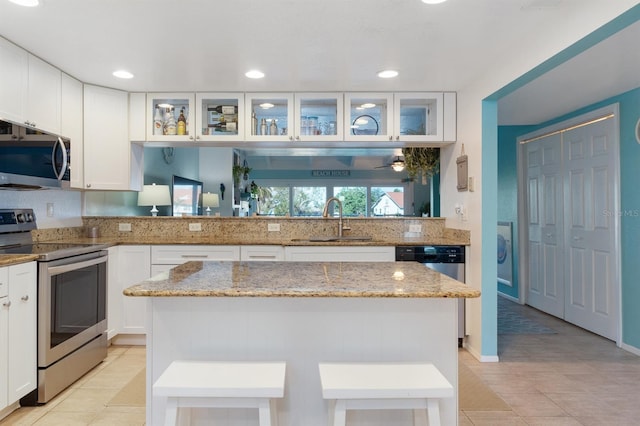 322 Windrush Blvd Unit 2, Indian Rocks Beach, FL 33785 - kitchen with stainless steel appliances, a sink, a kitchen island, glass insert cabinets, and recessed lighting