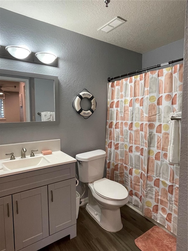 bathroom featuring vanity, toilet, wood-type flooring, and a textured ceiling