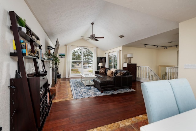 living room with lofted ceiling, rail lighting, ceiling fan, a textured ceiling, and dark hardwood / wood-style flooring