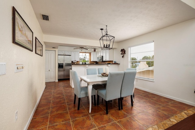 dining space featuring a textured ceiling, ceiling fan with notable chandelier, and a healthy amount of sunlight