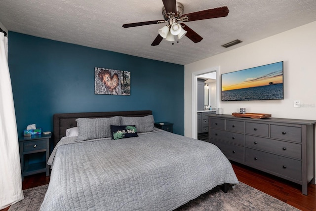 bedroom featuring ensuite bathroom, ceiling fan, a textured ceiling, and dark wood-type flooring