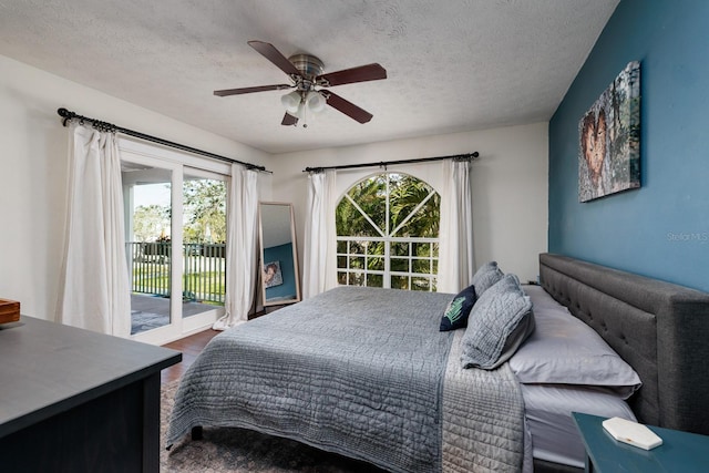 bedroom featuring access to outside, ceiling fan, dark wood-type flooring, and a textured ceiling