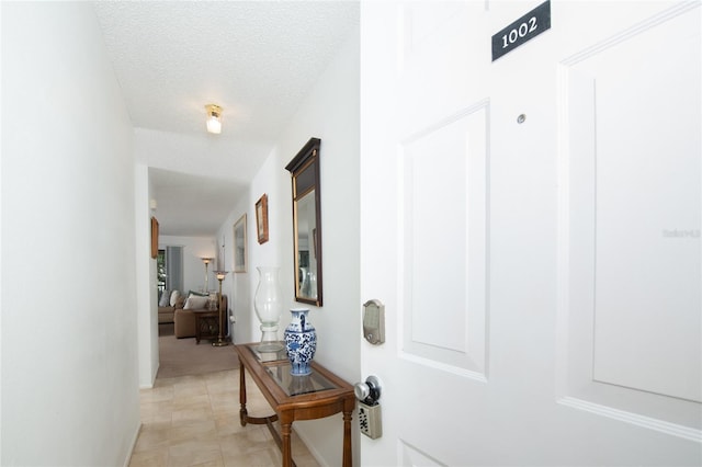 hallway featuring light tile patterned floors and a textured ceiling