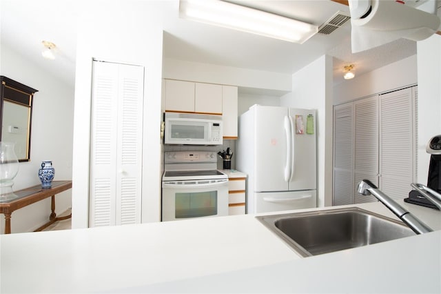 kitchen featuring white cabinetry, sink, and white appliances