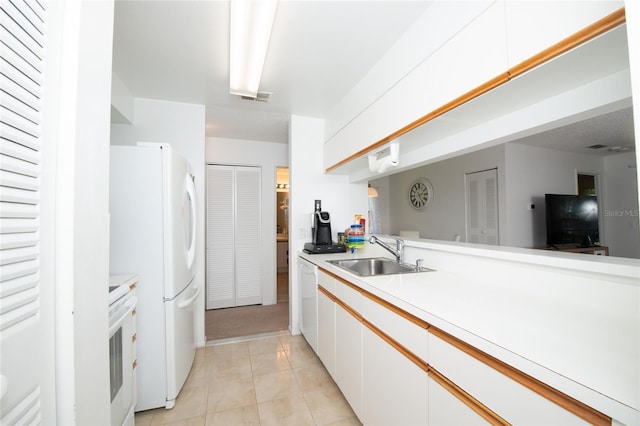 kitchen with white cabinetry, sink, light tile patterned flooring, and white appliances