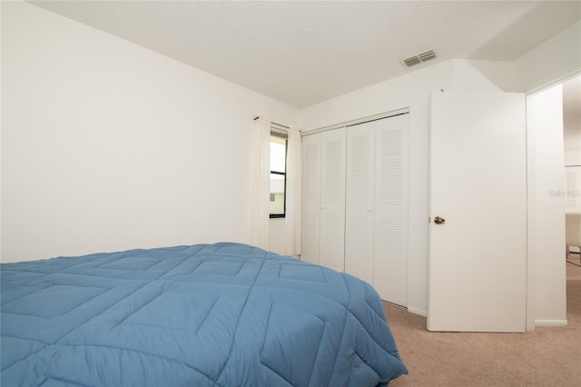 bedroom with light carpet, a textured ceiling, and a closet