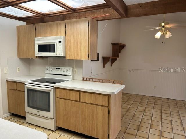 kitchen with white appliances, ceiling fan, light tile patterned floors, beamed ceiling, and kitchen peninsula