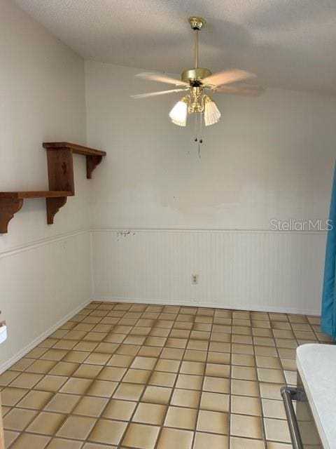 tiled empty room with a textured ceiling, ceiling fan, and lofted ceiling