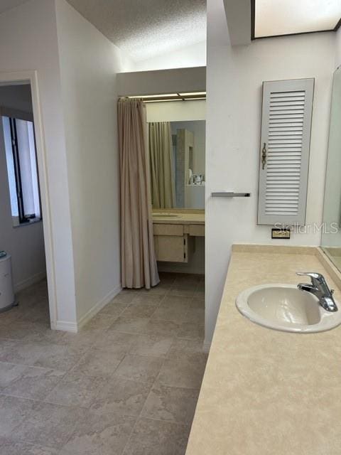 bathroom with vaulted ceiling, vanity, and a textured ceiling