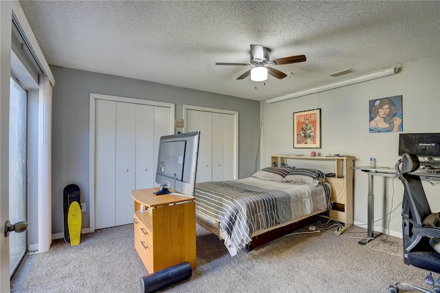 bedroom featuring ceiling fan, carpet floors, a textured ceiling, and multiple closets