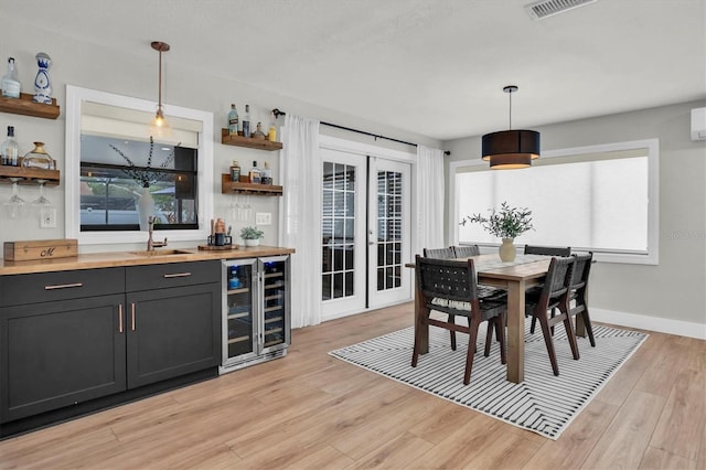 interior space with french doors, light hardwood / wood-style flooring, wine cooler, and indoor wet bar