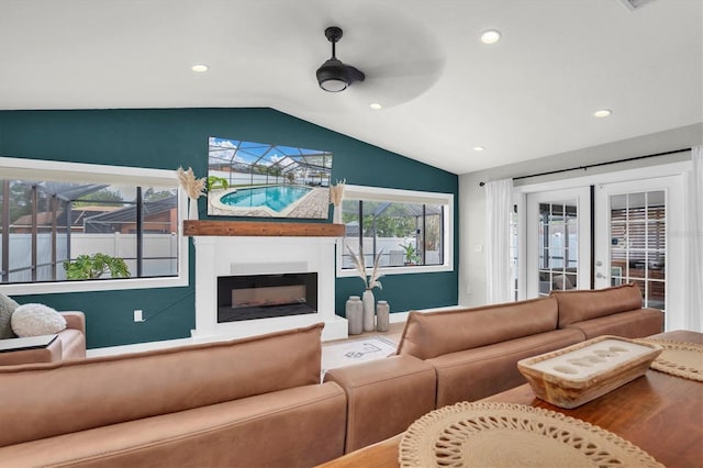 living room with a large fireplace, ceiling fan, french doors, and lofted ceiling