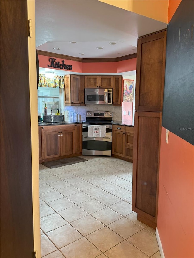 kitchen with light tile patterned floors, stainless steel appliances, tasteful backsplash, ornamental molding, and sink