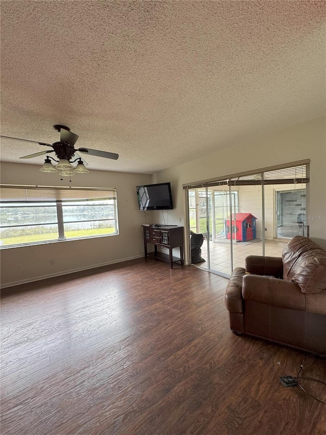 living room featuring a textured ceiling, ceiling fan, plenty of natural light, and dark hardwood / wood-style floors