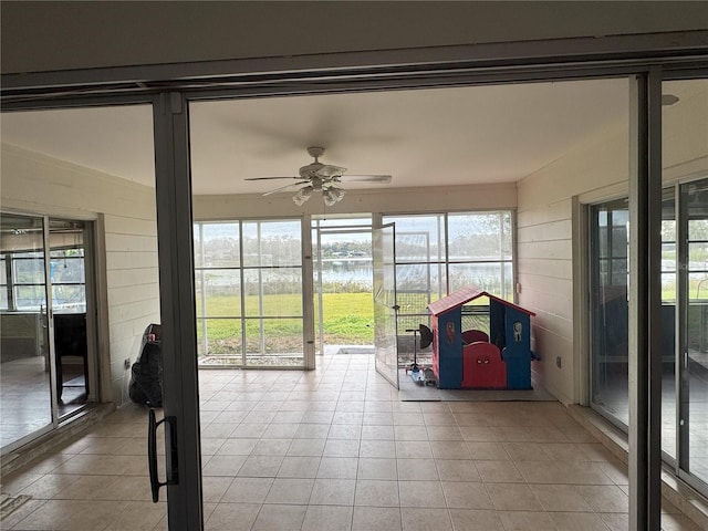 unfurnished sunroom featuring ceiling fan, a water view, and plenty of natural light