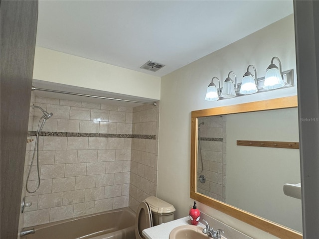 full bathroom featuring sink, tiled shower / bath combo, and toilet