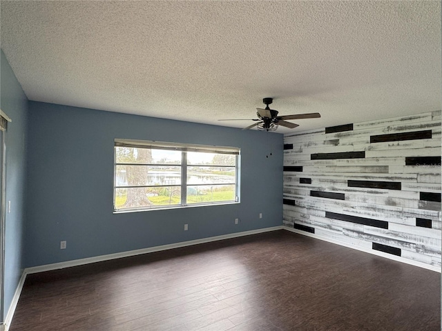 spare room featuring ceiling fan, a textured ceiling, dark hardwood / wood-style floors, and wood walls