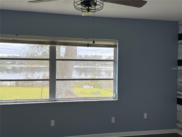 interior space featuring a textured ceiling, ceiling fan, and a water view