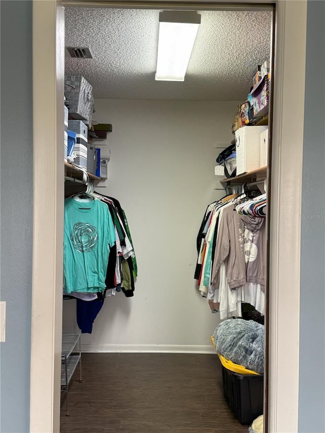 walk in closet with dark wood-type flooring