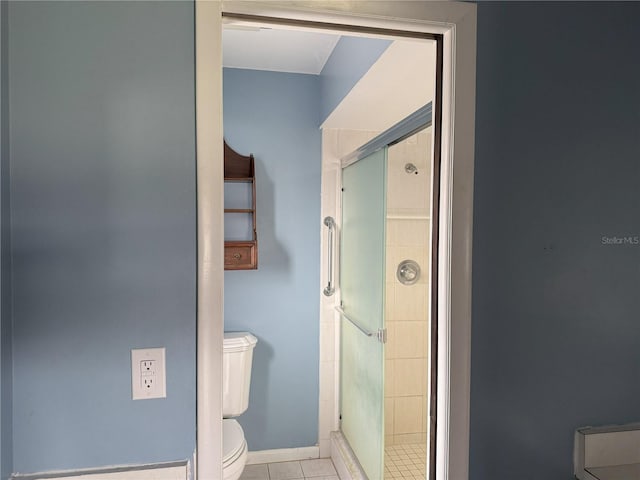 bathroom featuring toilet, tile patterned flooring, and a shower with shower door