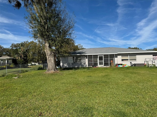 rear view of house featuring a sunroom and a yard