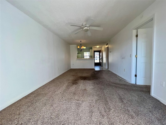 unfurnished living room with ceiling fan with notable chandelier, dark carpet, and a textured ceiling