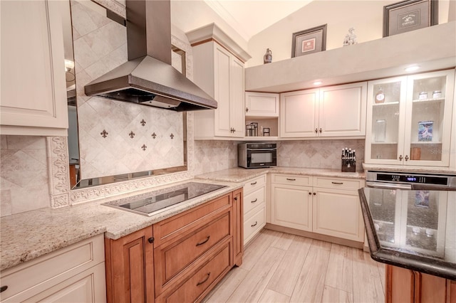 kitchen with oven, decorative backsplash, black electric stovetop, exhaust hood, and light stone counters