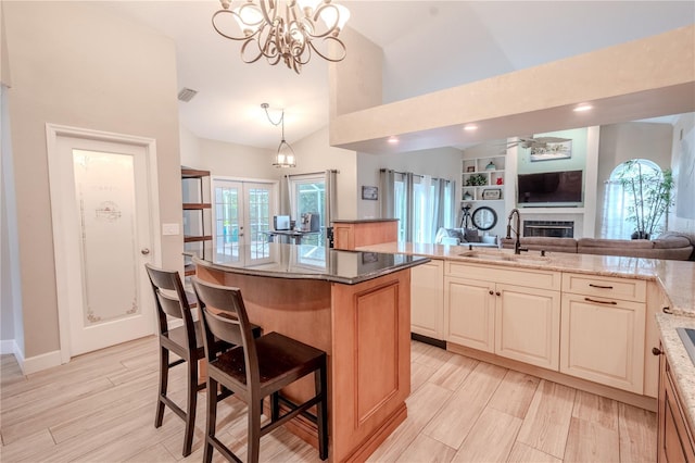 kitchen featuring sink, a breakfast bar, a center island, light stone countertops, and decorative light fixtures