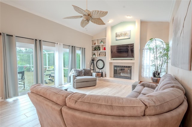 living room with vaulted ceiling, a tile fireplace, light hardwood / wood-style flooring, and a wealth of natural light