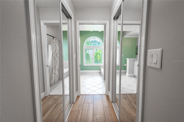 hall featuring light hardwood / wood-style flooring and a textured ceiling