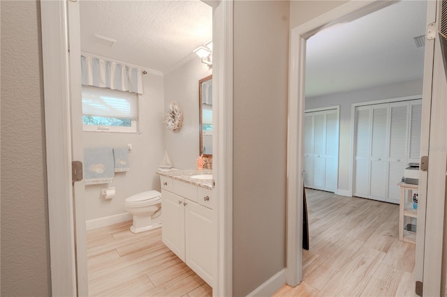 bathroom with hardwood / wood-style flooring, vanity, toilet, and a textured ceiling