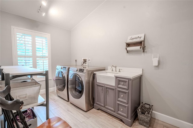 laundry room with sink, light hardwood / wood-style flooring, washing machine and dryer, cabinets, and a textured ceiling