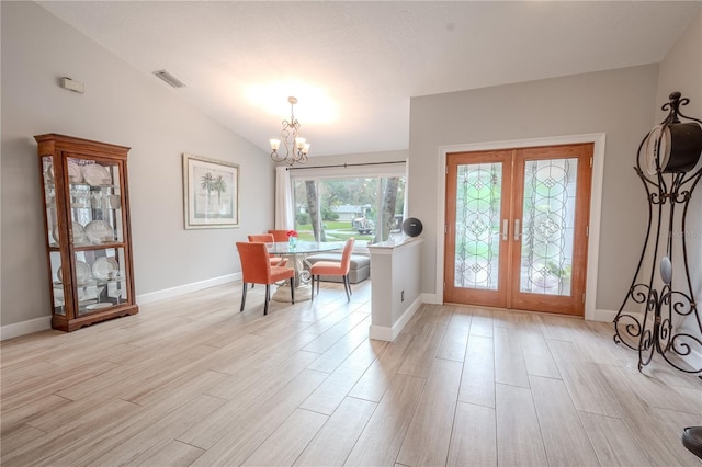 foyer entrance featuring vaulted ceiling, a notable chandelier, light wood-type flooring, and french doors