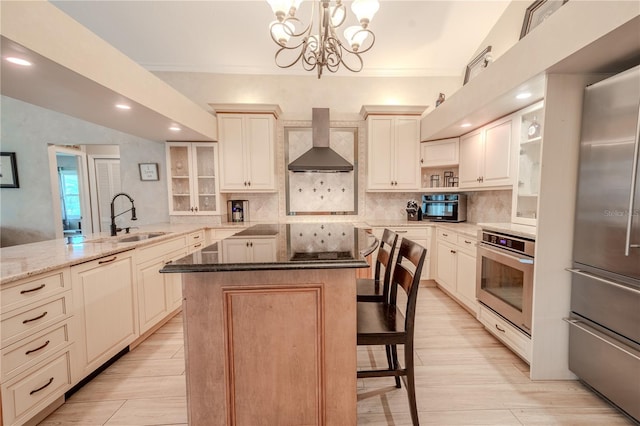 kitchen featuring a kitchen island, a breakfast bar, decorative light fixtures, stainless steel appliances, and wall chimney range hood