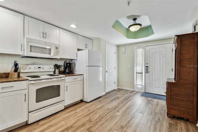 kitchen featuring light wood-type flooring, white appliances, white cabinetry, and dark stone countertops