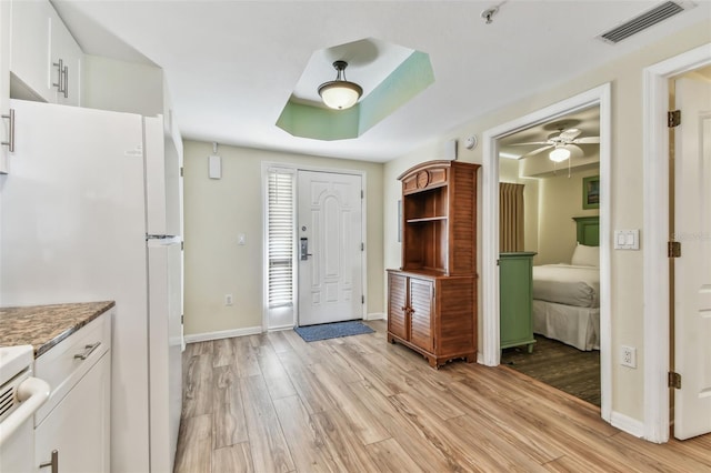 interior space featuring a raised ceiling, ceiling fan, and light hardwood / wood-style flooring