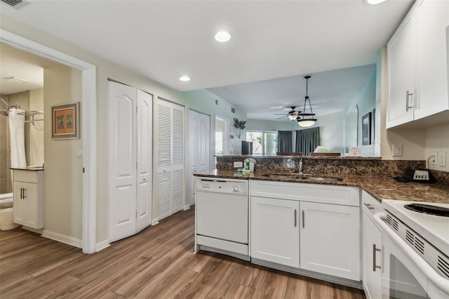 kitchen with white appliances, white cabinetry, dark stone countertops, and sink