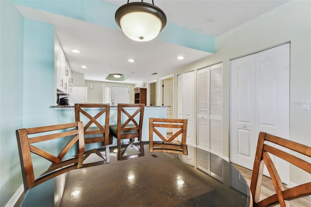 kitchen with kitchen peninsula, light hardwood / wood-style flooring, and white cabinetry