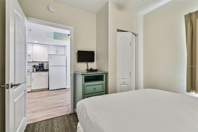 bedroom with hardwood / wood-style floors and white fridge