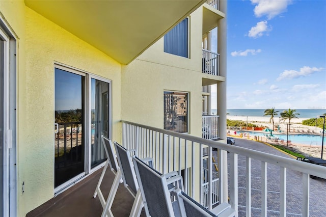 balcony featuring a beach view and a water view