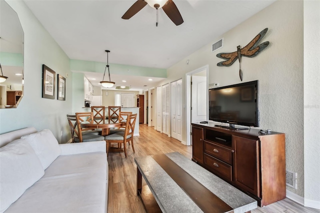 living room featuring ceiling fan and light hardwood / wood-style flooring