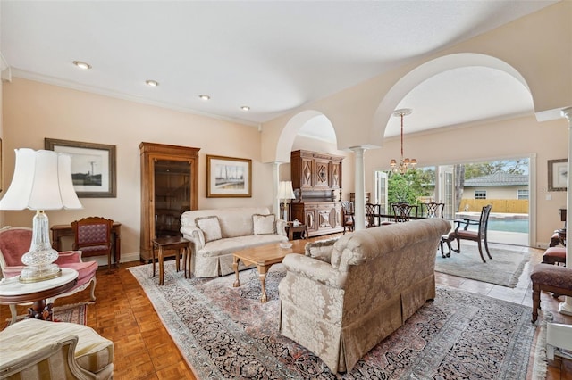 living room with a notable chandelier, ornamental molding, and decorative columns