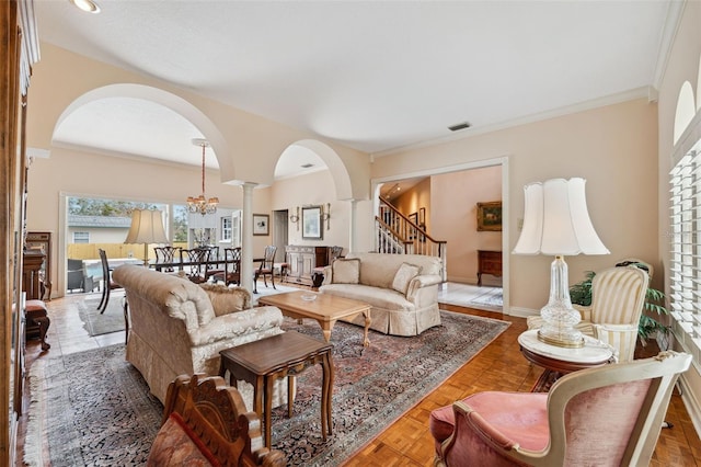 living room featuring a notable chandelier, parquet flooring, ornamental molding, and decorative columns