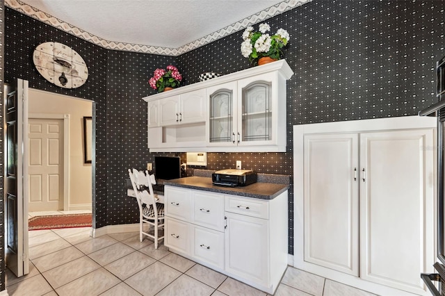 kitchen featuring white cabinetry, light tile patterned floors, and a textured ceiling