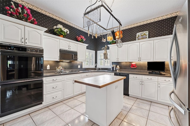 kitchen with a center island, sink, light tile patterned floors, white cabinets, and black appliances